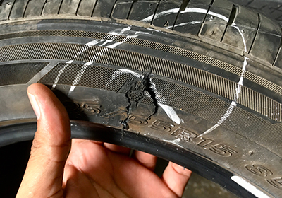 Markierter Riss in Seitenflanke eines Reifens Begutachtung mit der Hand